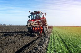 Tractor agricultural machine cultivating field.