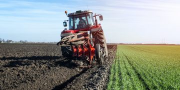 Tractor agricultural machine cultivating field.