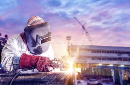 double exposure concept, worker arc welder piping welding buiding in shipyard background soft monotone