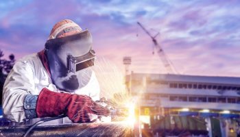 double exposure concept, worker arc welder piping welding buiding in shipyard background soft monotone